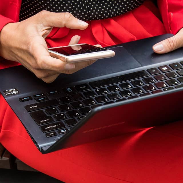 Eine Frau hält ein Smartphone und ein Laptop in den Händen